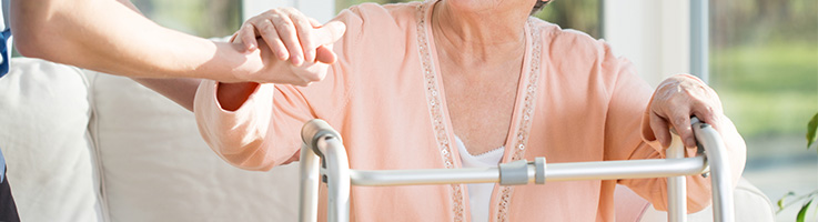nurse helping an old woman with a walker stand up