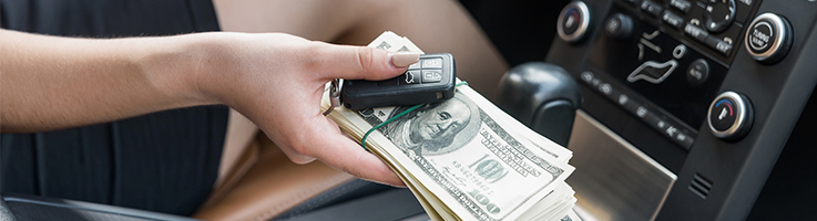 woman holding money and keys in car